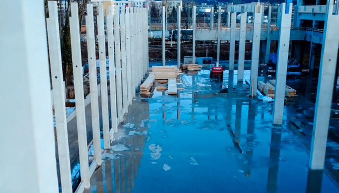 Innenansicht der Baustelle mit hohen Betonstützen und vorbereiteter Hallenfläche während der Rohbauphase.