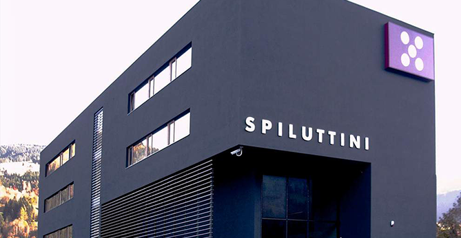 Modernes Gewerbegebäude von Spiluttini mit dunkler Fassade, horizontalen Fensterbändern und markantem Eingangsbereich.